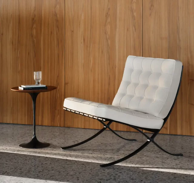 Weißer Barcelona Chair neben schwarzen Beistelltisch von Knoll International.