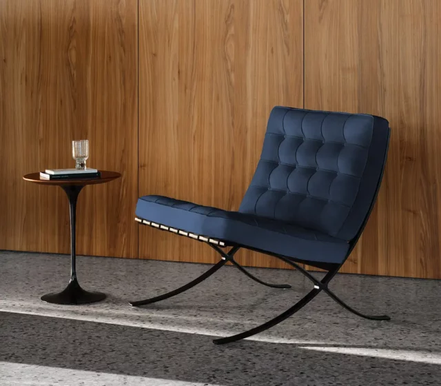 Blauer Barcelona Chair und Beistelltisch von Knoll International vor einer Holzwand.