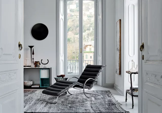 Heller Raum mit einer schwarzen Liege von Knoll International vor einem großen Fenster.